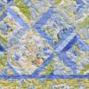 A striking geometric quilt in blue, green and yellow who's pattern was taken from the book 'StrataVarious Quilts'.